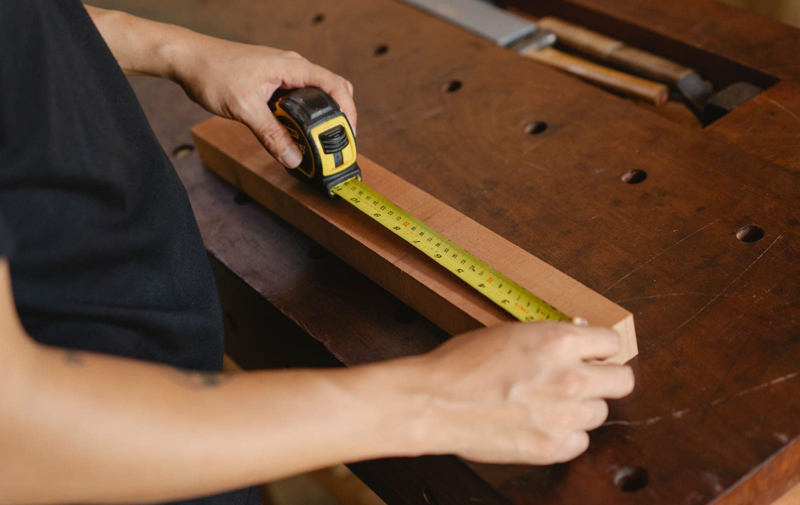 A carpenter measuring a piece of timber with a ruler